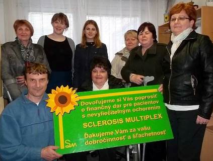 A group of people post for a photo with a sign in Slovakian